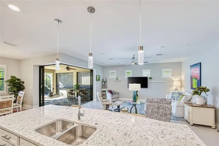 Kitchen featuring light stone countertops, ceiling fan, open floor plan, hanging light fixtures, and recessed lighting