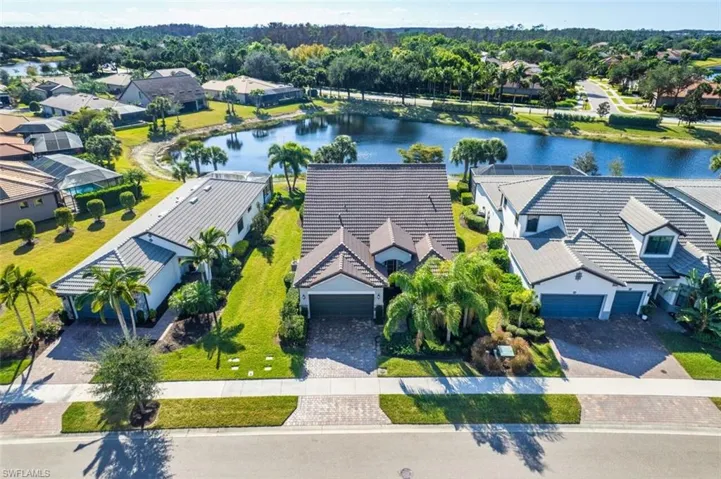 Aerial perspective of suburban area with a nearby body of water and a tree filled landscape