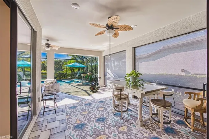 Sunroom / solarium with outdoor dining space, a ceiling fan, and a patio area