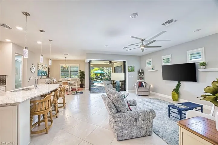 Living room with a ceiling fan, light tile patterned flooring, and recessed lighting