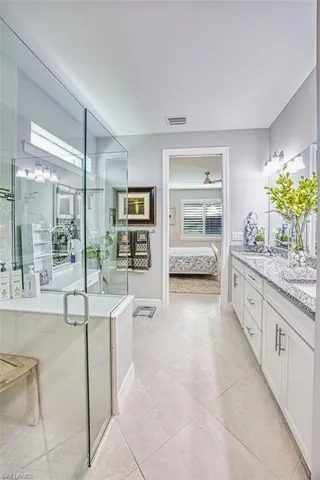 Ensuite bathroom with double vanity, a shower stall, and light tile patterned flooring