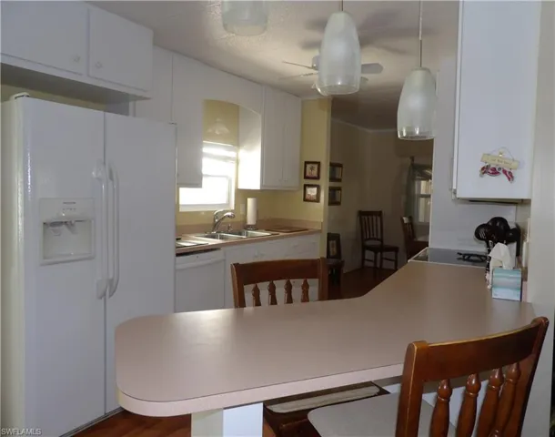Kitchen featuring white appliances, a peninsula, a kitchen breakfast bar, and light countertops