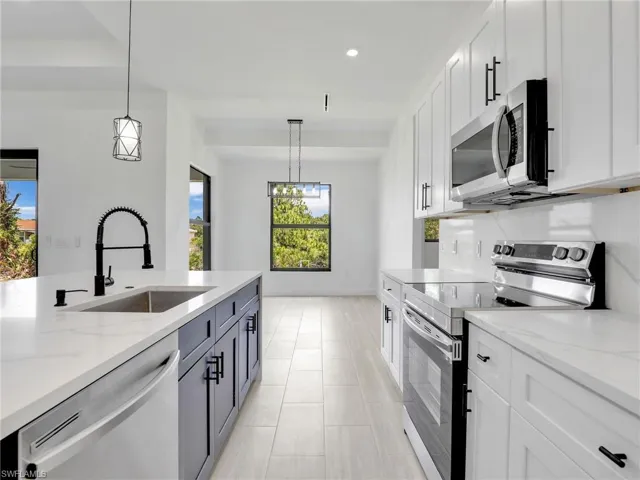 Kitchen with decorative light fixtures, white cabinets, and stainless steel appliances
