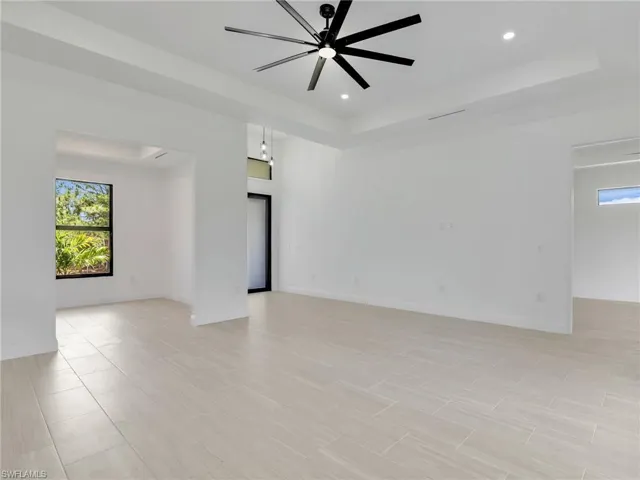 Tiled empty room featuring ceiling fan and a tray ceiling