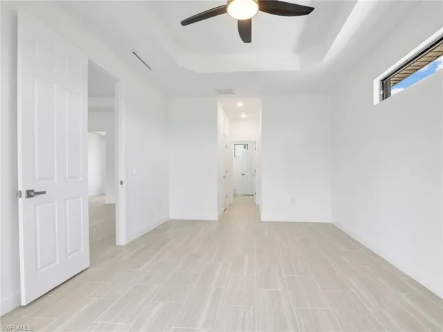 Tiled spare room featuring a raised ceiling and ceiling fan