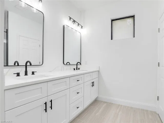Bathroom with tile floors, double sink, and vanity with extensive cabinet space