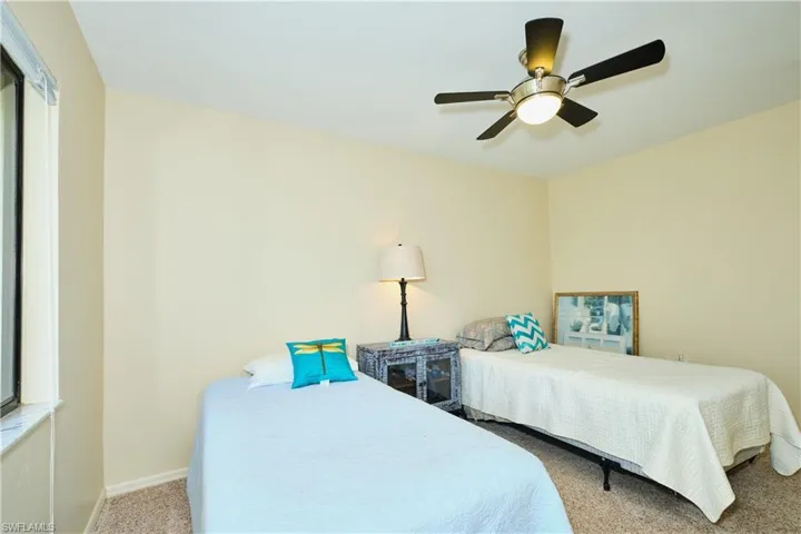 Carpeted bedroom with ceiling fan and baseboards