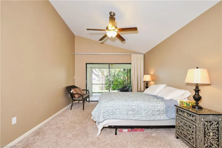 Carpeted bedroom with baseboards, vaulted ceiling, and a ceiling fan