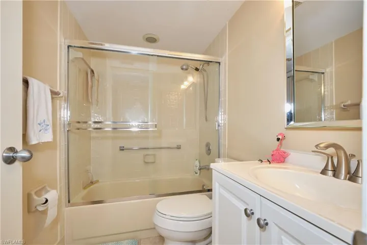 Full bathroom featuring enclosed tub / shower combo, vanity, and toilet