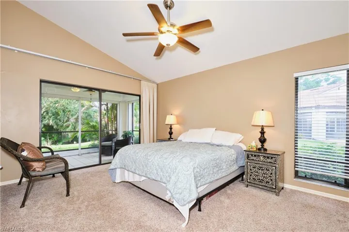 Carpeted bedroom with lofted ceiling, access to outside, multiple windows, and baseboards