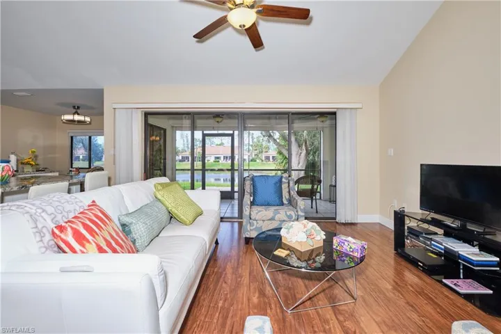 Living room with vaulted ceiling, ceiling fan, baseboards, and wood finished floors