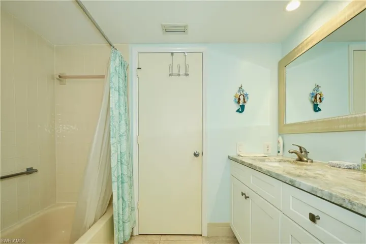 Full bath with visible vents, shower / bath combo with shower curtain, vanity, tile patterned flooring, and baseboards