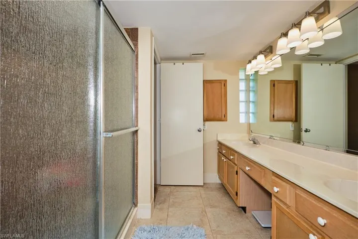 Bathroom with a stall shower, tile patterned flooring, visible vents, and a sink