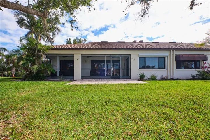 Rear view of house with a sunroom, a tiled roof, and a yard