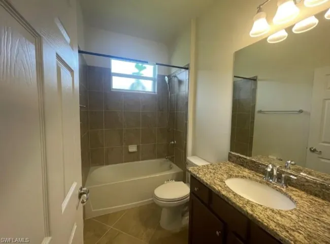 Bathroom featuring toilet, washtub / shower combination, tile patterned floors, and vanity