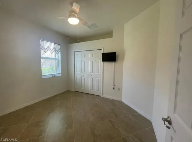 Unfurnished bedroom featuring a closet, baseboards, a ceiling fan, and tile patterned flooring