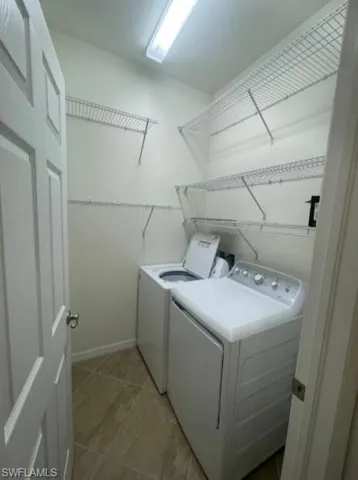 Laundry area featuring laundry area, baseboards, tile patterned flooring, and washing machine and dryer