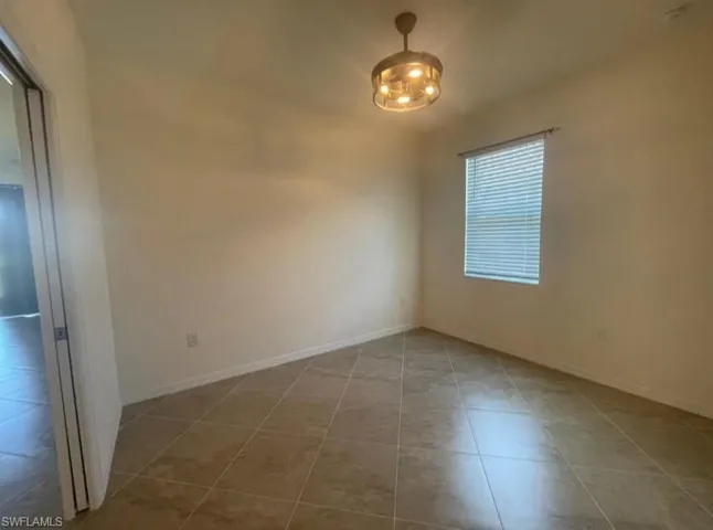 Empty room featuring baseboards and tile patterned flooring