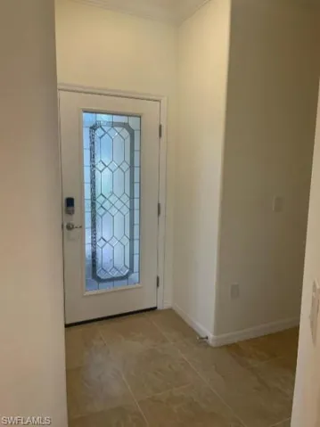 Tiled foyer entrance with baseboards and crown molding