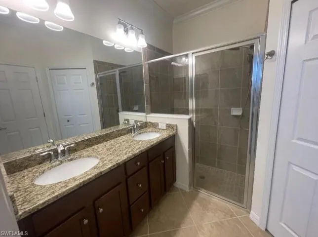 Full bathroom with crown molding, a sink, a stall shower, and tile patterned floors
