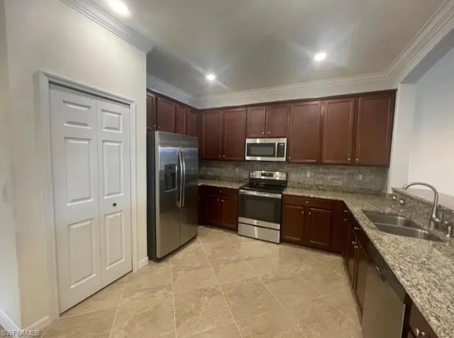 Kitchen with ornamental molding, a sink, backsplash, and stainless steel appliances