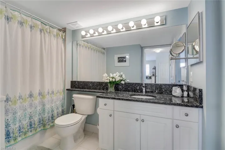 Bathroom with vanity, light tile patterned flooring, and shower / tub combo with curtain