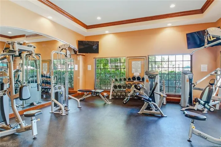 Gym featuring ornamental molding, a tray ceiling, and recessed lighting
