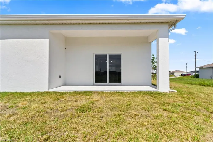 Back of property with stucco siding, a lawn, and a patio