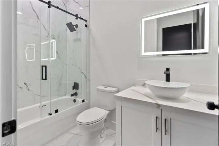 Full bath with vanity, bath / shower combo with glass door, and marble finish floors