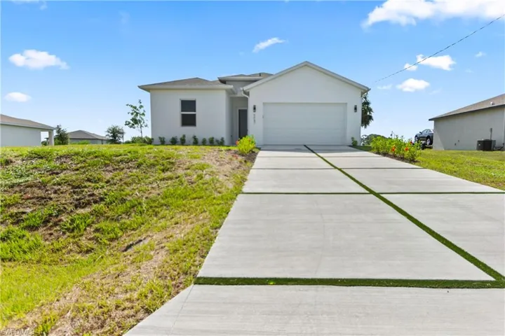 Ranch-style home featuring a garage, driveway, and stucco siding