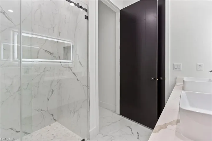 Full bathroom featuring a marble finish shower and marble tiled floors