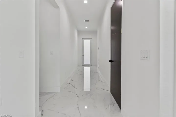 Hallway featuring recessed lighting and light marble finish floors