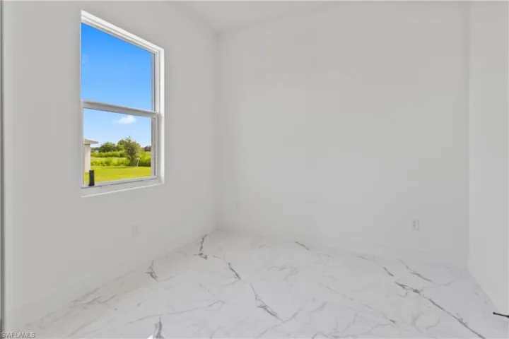 Unfurnished room featuring marble look tile flooring and baseboards