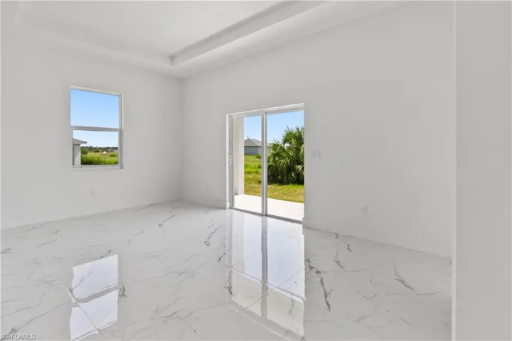 Unfurnished room with plenty of natural light, a tray ceiling, and marble tiled flooring