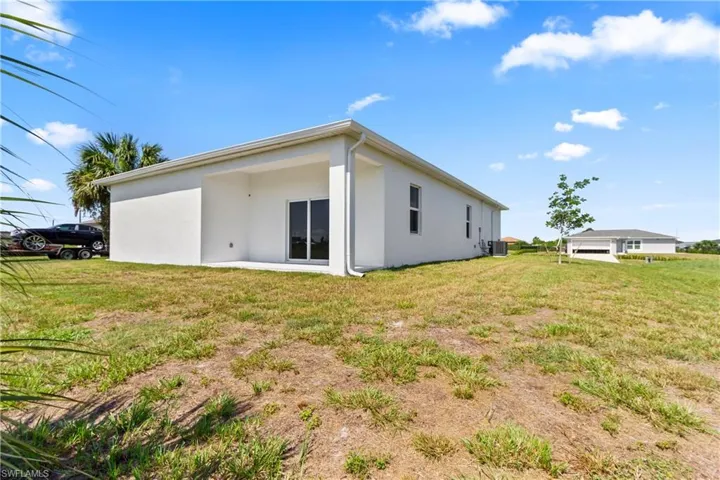 Back of property with stucco siding and a yard