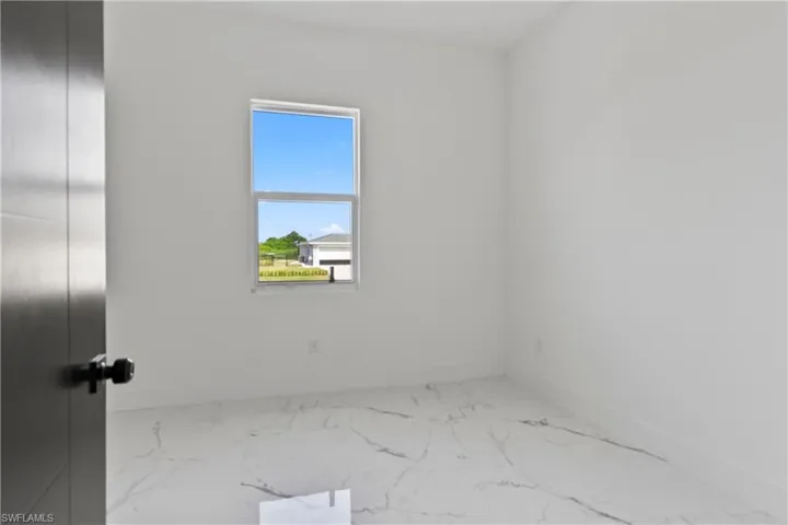 Empty room with marble look tile flooring and baseboards