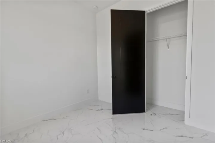 Unfurnished bedroom with marble finish flooring and a closet