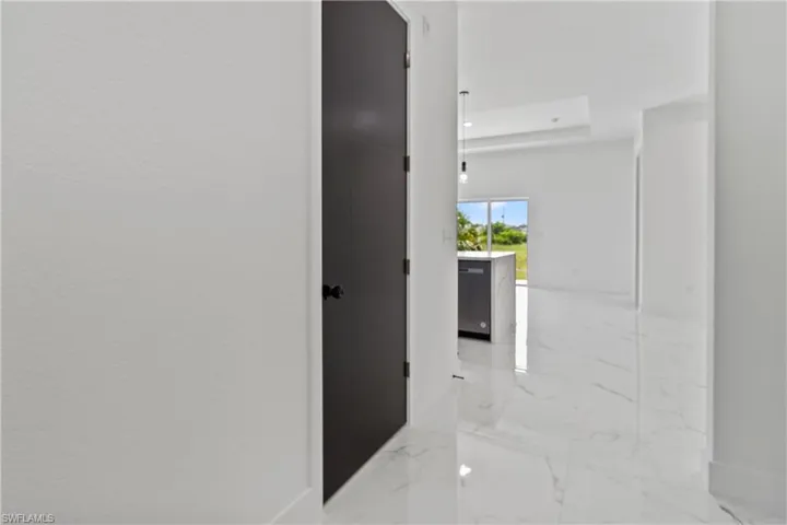 Hall featuring marble tiled floors, a raised ceiling, and recessed lighting
