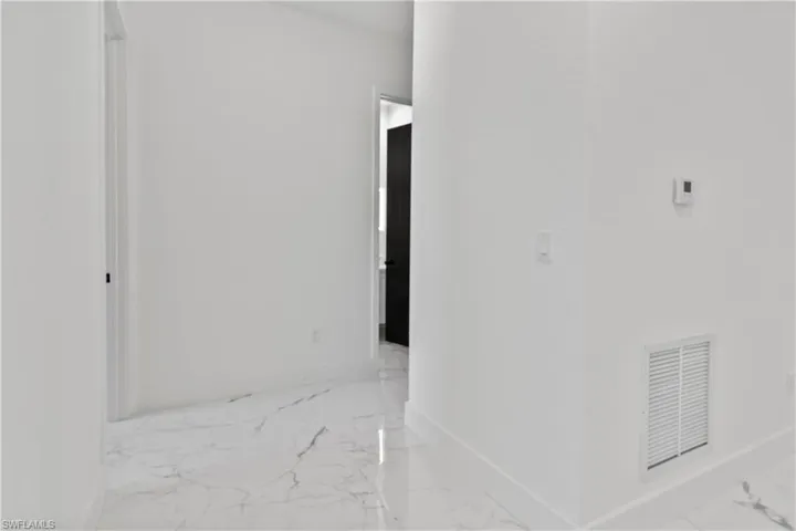 Corridor featuring marble finish floors and baseboards