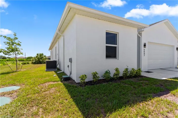 View of home's exterior featuring a garage, stucco siding, a lawn, and concrete driveway