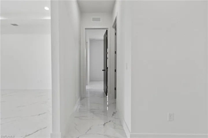 Hallway with marble finish flooring and recessed lighting