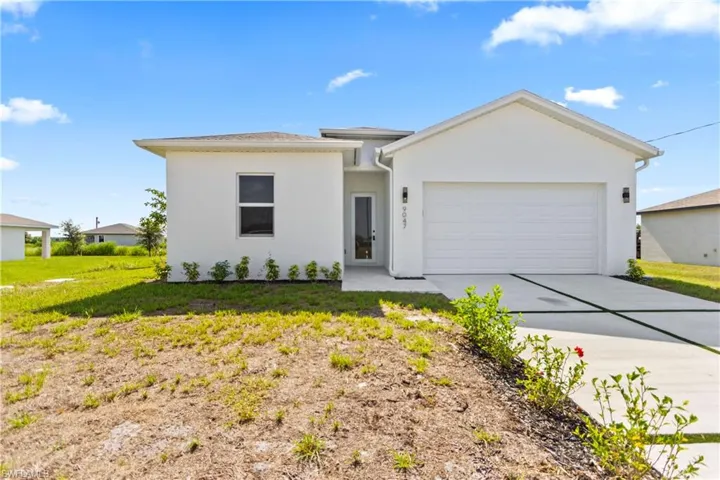 View of front of house featuring a garage, concrete driveway, stucco siding, and a front yard