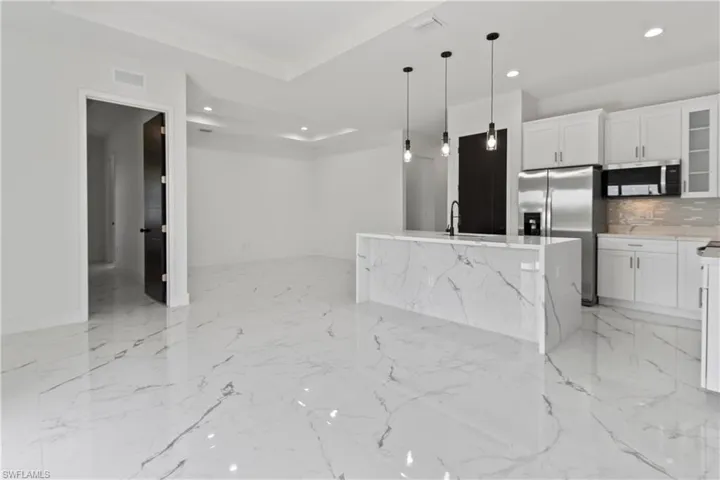 Kitchen featuring recessed lighting, appliances with stainless steel finishes, white cabinets, glass insert cabinets, and hanging light fixtures