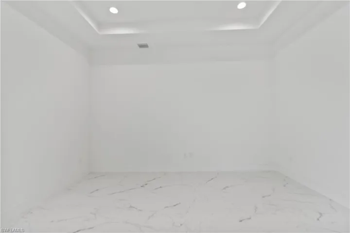 Unfurnished room featuring recessed lighting, marble finish flooring, and a raised ceiling