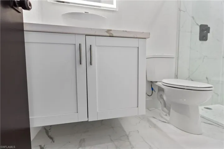 Full bath with marble look tile flooring, vanity, and a marble finish shower