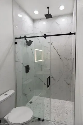 Full bathroom featuring a marble finish shower and recessed lighting