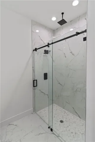 Bathroom with marble look tiles, a marble finish shower, and recessed lighting