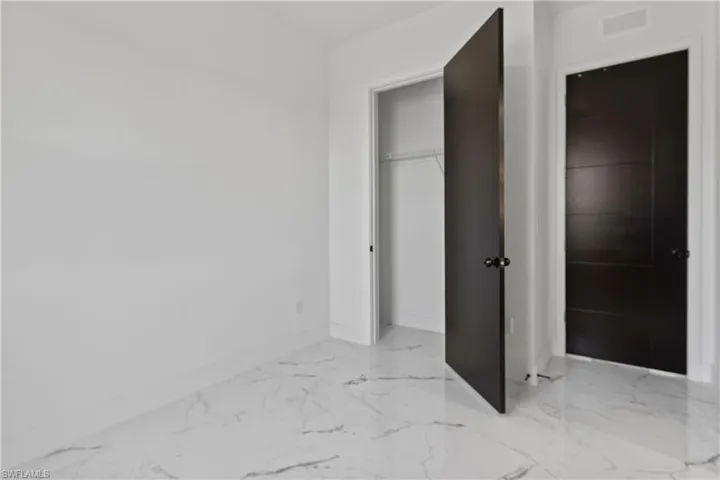 Unfurnished bedroom with light marble finish flooring and a closet