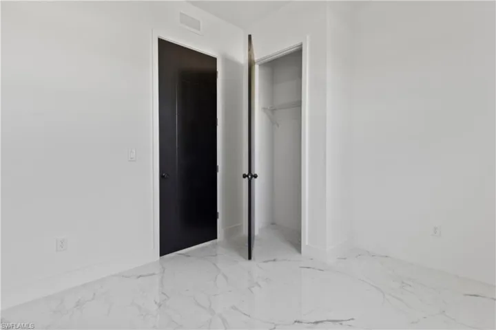 Unfurnished bedroom featuring marble finish floors and a closet