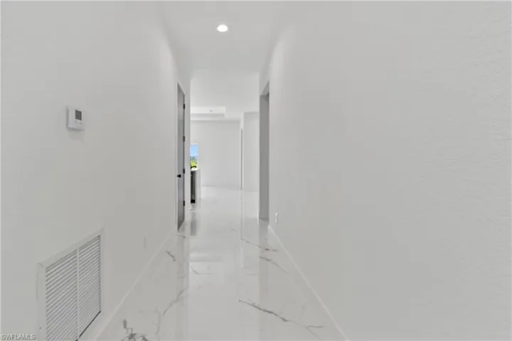 Hall featuring light marble finish flooring and recessed lighting